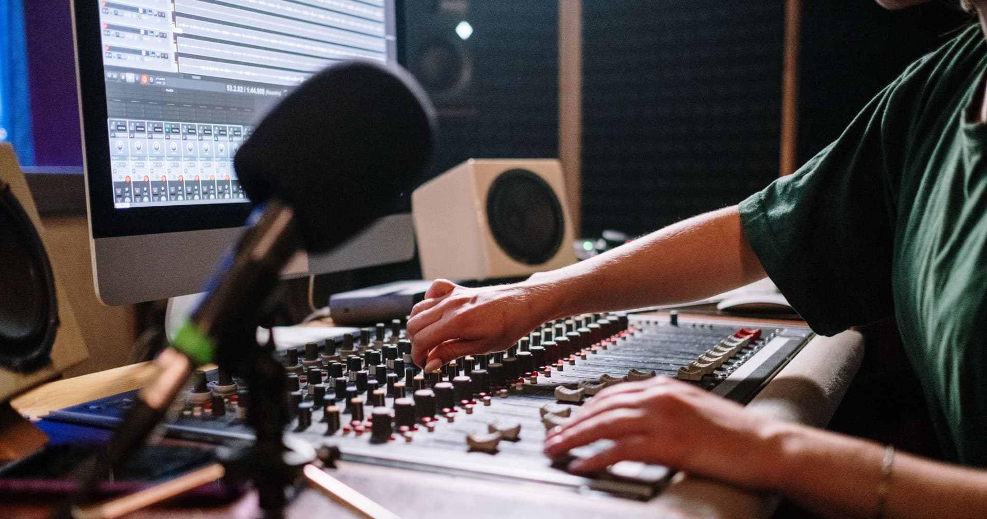 Audio engineer adjusting faders on a studio mixing console